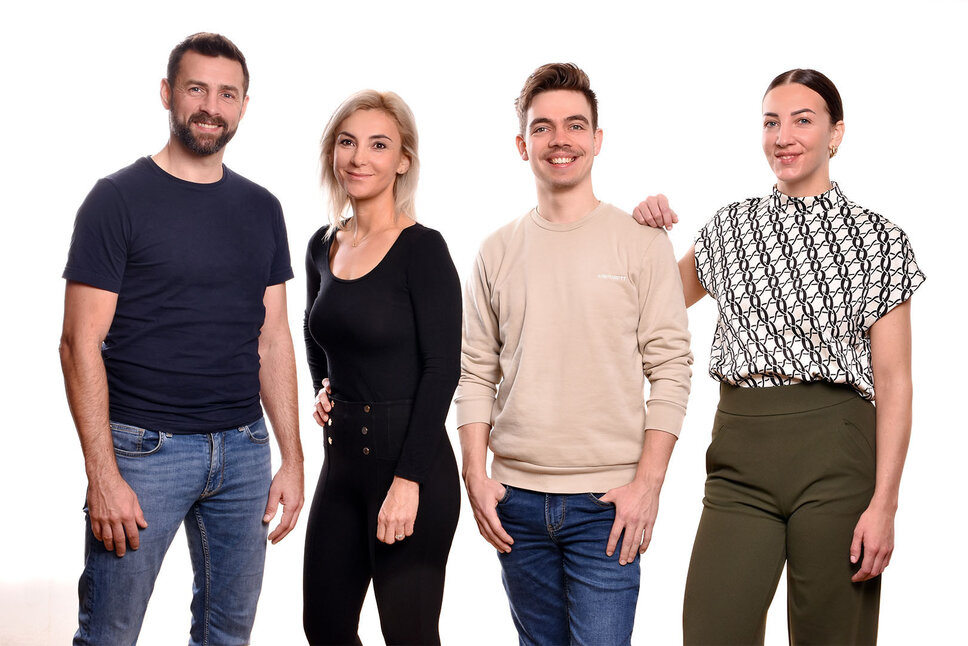 Two female and two male employees of the company weba Werkzeugbau are standing side by side, smiling warmly at the camera. They appear relaxed and confident, reflecting a positive work environment. Jobs in Steyr for experienced professionals at weba Werkzeugbau in a strong team community.