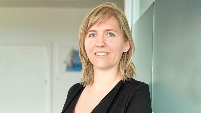 Porträt von Tanja Burghuber, Personalmanagerin bei weba Werkzeugbau, entspannt an einer Milchglaswand in Dietach lehnend, mit einem professionellen und freundlichen Ausdruck, betont durch die weiche Beleuchtung und den verschwommenen Hintergrund. Das Foto wird im Kontaktbereich der Stellenangebote in Steyr von weba Werkzeugbau verwendet.